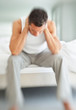 Blurred man suffering with bad neck pain while sitting on bed