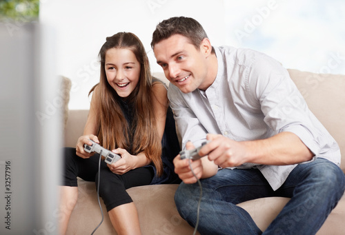 Foto: Happy father and daughter playing video games at home Happy father and daughter playing video games at home