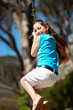 Cheerful little girl swinging on a rope in countryside