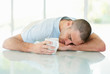 Tired middle aged man sleeping with cup of coffee or tea in hand