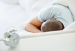 Middle aged man sleeping in bed with blur alarm clock on table