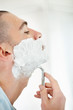 Middle aged man shaving his beard with razor