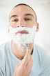 A middle aged guy using a razor to shave his beard