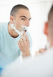 Middle aged man looking at mirror while shaving his beard