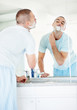 Middle aged man looking at bathroom mirror while shaving self