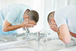 Middle aged man washing his face with water in a bathroom