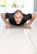 Fit man lying on mat and doing push-ups at gym