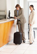 Business couple waiting at the hotel reception with luggage
