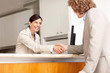 Receptionist shaking hands with businessman at hotel reception