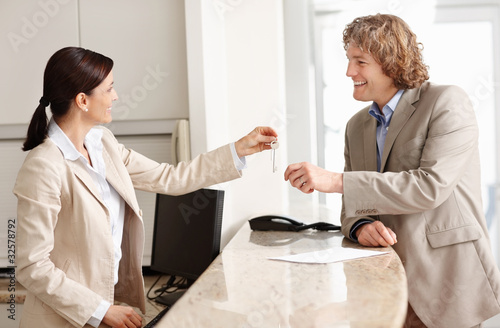 Foto: Mature receptionist giving keys to a happy mature businessman Mature receptionist giving keys to a happy mature businessman