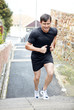 Young tired athlete during runnig on stairs