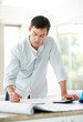 Smart young male architect working on diagrams and blueprint