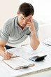 Young male architect writing on paper in office