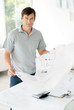 Happy young man standing in office and  holding blue print