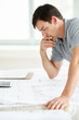Thoughtful male engineer working on old blueprint