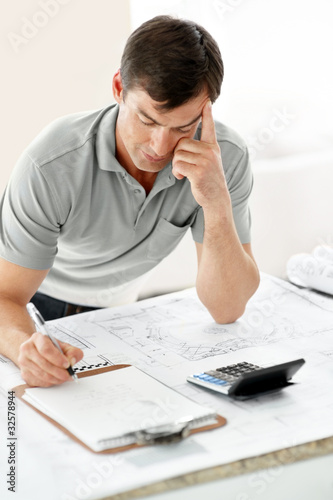 Foto: Young male architect writing on paper in office Young male architect writing on paper in office