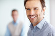 Happy middle aged executive with a man in blurred background
