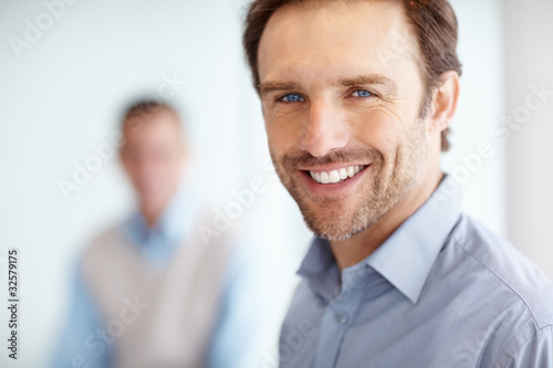 Photo: Happy middle aged executive with a man in blurred background Happy middle aged executive with a man in blurred background