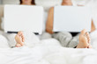 Couple sitting on bed and using laptop
