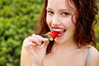 Foto: Beautiful young lady eating a strawberry Beautiful young lady eating a strawberry