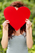 Young girl covering her face with red heart