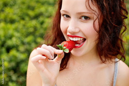 Foto: Beautiful young lady eating a strawberry Beautiful young lady eating a strawberry