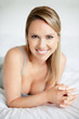 Young smiling temptress lying in bed