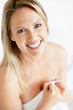 Smiling female holding a bed sheet over her nude body