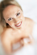 Happy female holding a bed sheet over her naked body