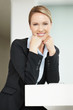 Cute young business woman sitting with hands on chin