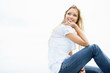 Happy thoughtful female sitting against the bright sky