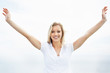 Smiling young female with hands raised against the sky
