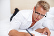 Man taking notes in bed