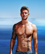 Young muscular man standing against sky