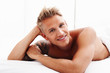 Young man relaxing in bed and smiling