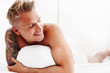 Man in bed cuddling his pillow and smiling