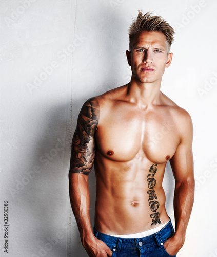 Photo: Shirtless guy standing near wall Shirtless guy standing near wall