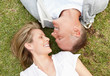 Happy mature couple lying on grass while looking at each other