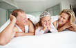 An innocent girl wearing crown with her parentss in bed at home