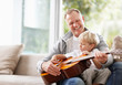 Photo : Little boy playing guitar with his father at home Little boy playing guitar with his father at home