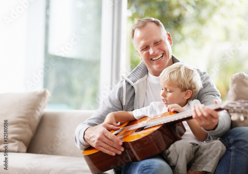 Foto: Little boy playing guitar with his father at home Little boy playing guitar with his father at home