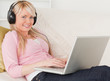 Pretty woman listening to music on her headphones while lying on