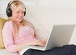 Attractive female listening to music on her headphones while lyi