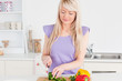 Beautiful blonde female cutting vegetables in modern kitchen int