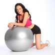 Sexy young woman kneeling with fitness ball