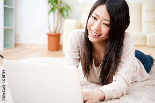 Photo: beautiful asian woman using a laptop computer beautiful asian woman using a laptop computer