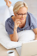 Young lady lying on the floor and using laptop