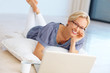 Happy young woman lying on floor with a laptop