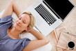 Pretty young lady relaxing on the floor beside a laptop