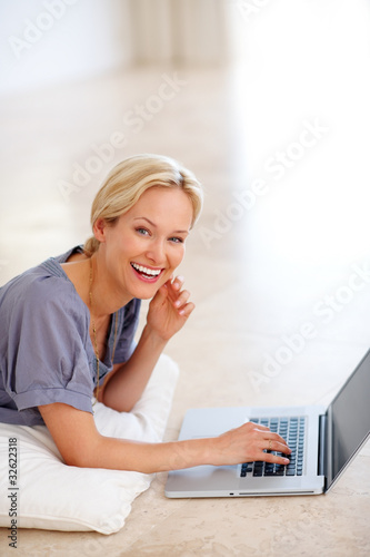 Photo: Young lady lying on the floor and working on laptop Young lady lying on the floor and working on laptop